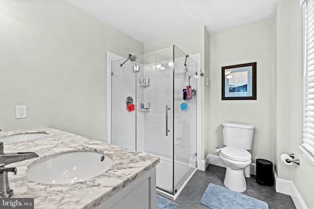 bathroom featuring a shower stall, toilet, tile patterned floors, double vanity, and baseboards