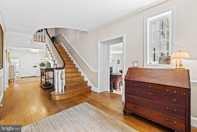 foyer featuring stairway, wood-type flooring, healthy amount of natural light, and ornamental molding