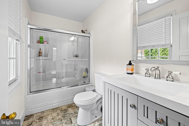 bathroom with toilet, bath / shower combo with glass door, vanity, and stone finish floors