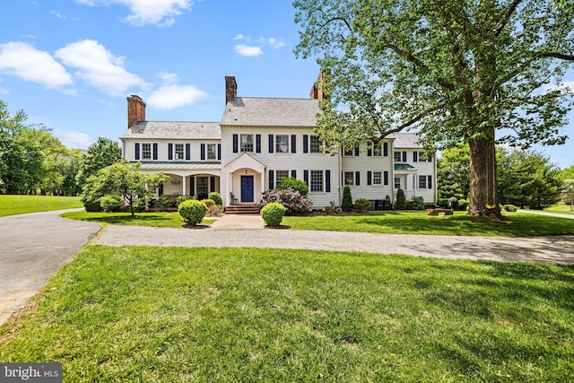 colonial home featuring a front lawn and a chimney