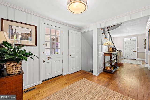 entrance foyer featuring stairs, ornamental molding, hardwood / wood-style flooring, and baseboards