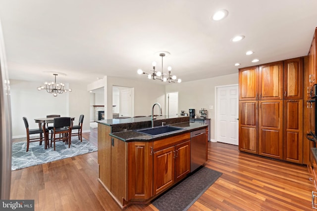 kitchen with wood finished floors, a chandelier, stainless steel dishwasher, and a sink