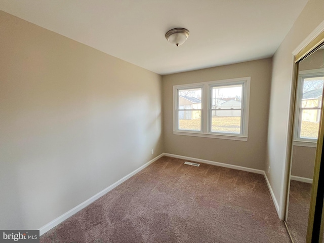 empty room featuring baseboards, visible vents, and carpet