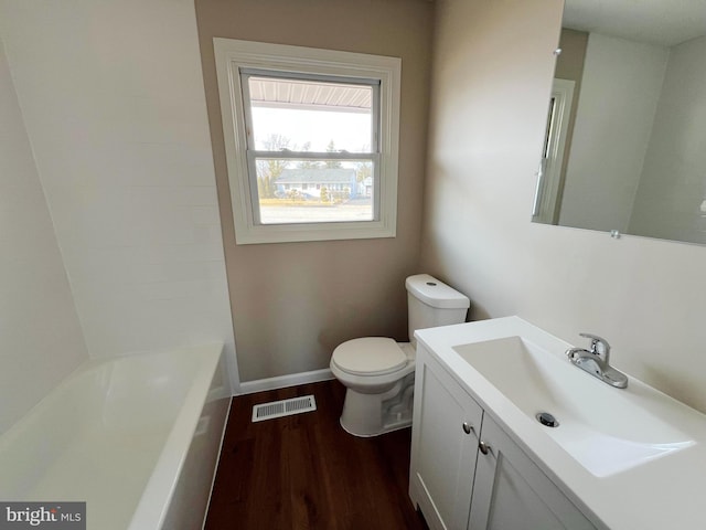 bathroom featuring wood finished floors, visible vents, toilet, vanity, and baseboards