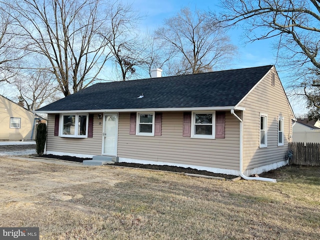 view of front of property featuring fence, a chimney, roof with shingles, and a front yard