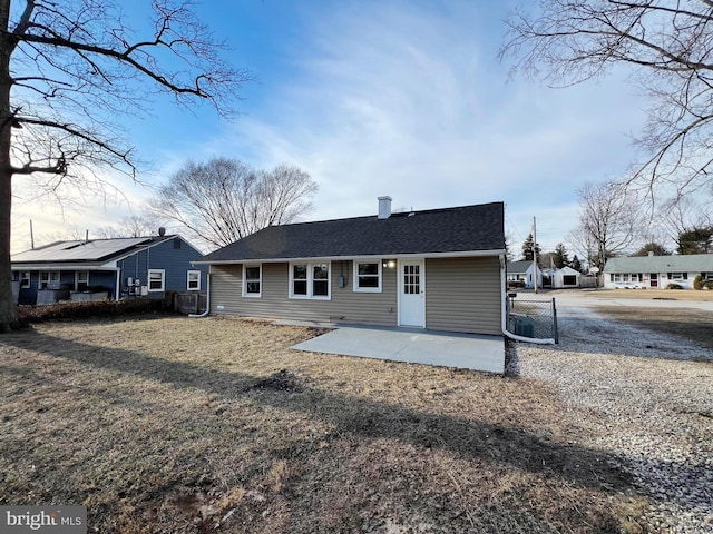 rear view of house featuring fence, a patio, and a shingled roof