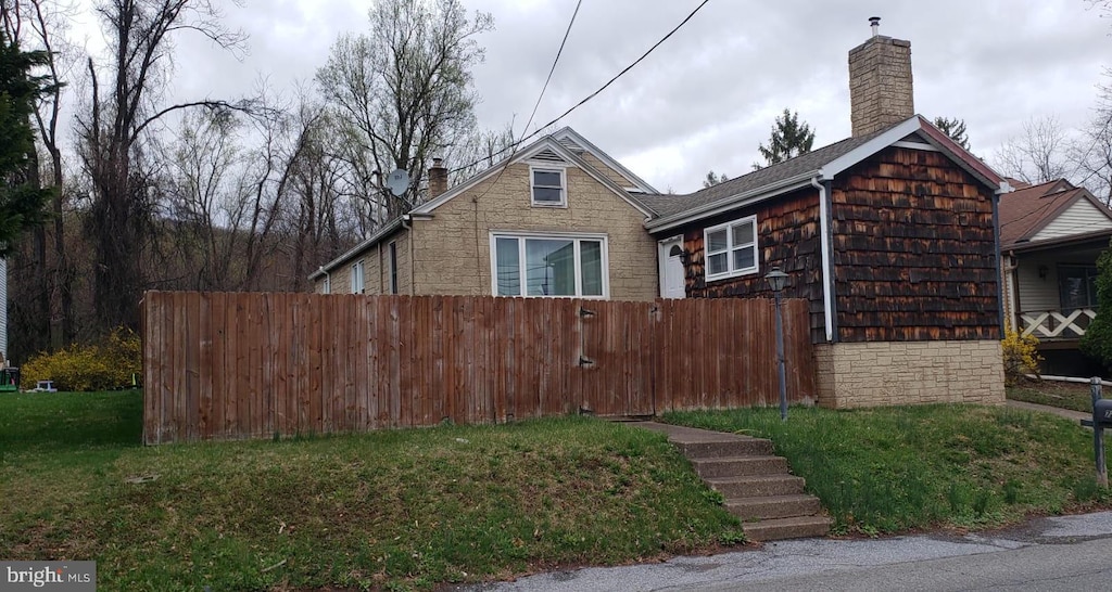 view of property exterior featuring a chimney, fence, a yard, and stone siding