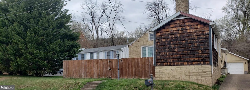 view of property exterior featuring fence, a chimney, and a detached garage