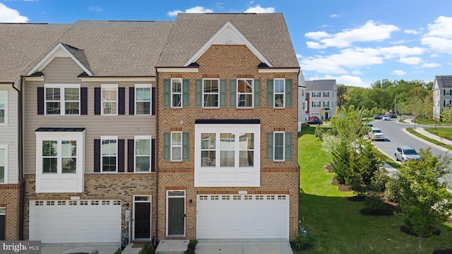 townhome / multi-family property featuring an attached garage, a front yard, driveway, and brick siding