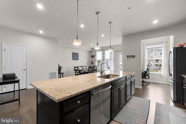 kitchen with an island with sink, dark wood-style floors, dark cabinetry, a sink, and stainless steel appliances