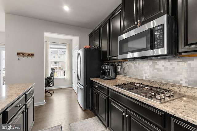 kitchen with decorative backsplash, dark cabinetry, stainless steel appliances, and a wealth of natural light