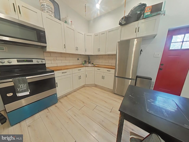 2113 N 17th St, Philadelphia, PA 19121 - kitchen featuring decorative backsplash, appliances with stainless steel finishes, white cabinets, light wood finished floors, and butcher block counters