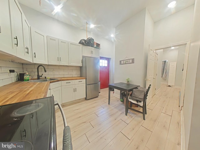 2113 N 17th St, Philadelphia, PA 19121 - kitchen featuring freestanding refrigerator, electric range, butcher block counters, decorative backsplash, and a sink