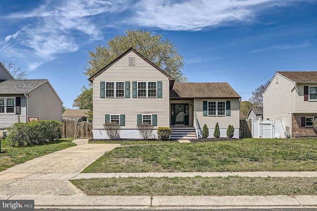 split level home with a gate, fence, and a front yard