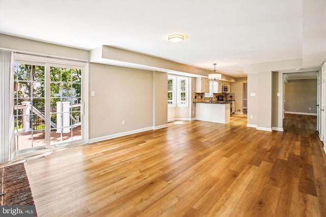 21130 Haystack Ct, Ashburn, VA 20147 - unfurnished living room featuring baseboards, a chandelier, light wood-type flooring, and a sink