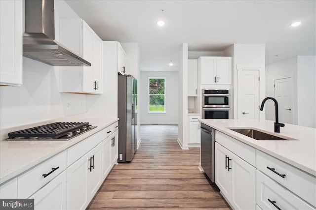 9842 Fire Tower Rd, Ijamsville, MD 21754 - kitchen with wall chimney range hood, appliances with stainless steel finishes, a sink, light wood-type flooring, and white cabinetry