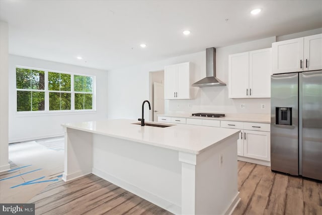 9842 Fire Tower Rd, Ijamsville, MD 21754 - kitchen with wall chimney range hood, appliances with stainless steel finishes, a sink, light wood-style flooring, and an island with sink