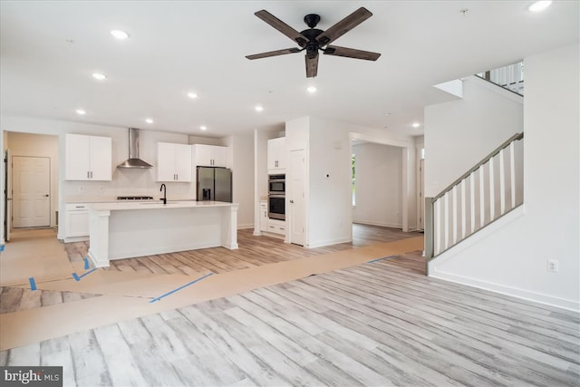 9842 Fire Tower Rd, Ijamsville, MD 21754 - kitchen with wall chimney range hood, open floor plan, recessed lighting, light wood finished floors, and white cabinets