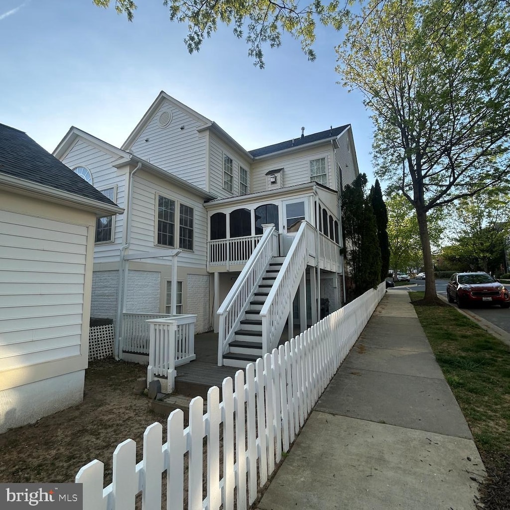 rear view of property with fence, stairs, and a sunroom