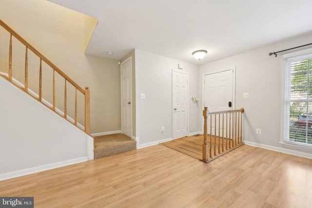 foyer entrance with stairway, light wood-style flooring, and baseboards