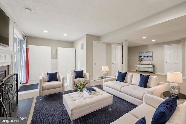 living area featuring a glass covered fireplace, visible vents, and recessed lighting