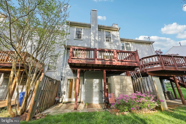 rear view of property featuring a deck, a chimney, fence, stairway, and central AC