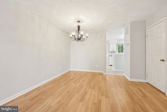 unfurnished dining area featuring baseboards, light wood-type flooring, and a notable chandelier
