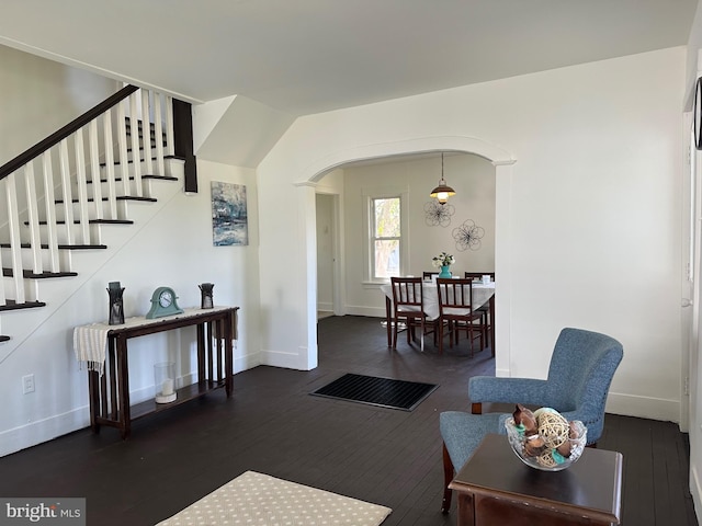 living area with wood-type flooring, arched walkways, baseboards, and stairs