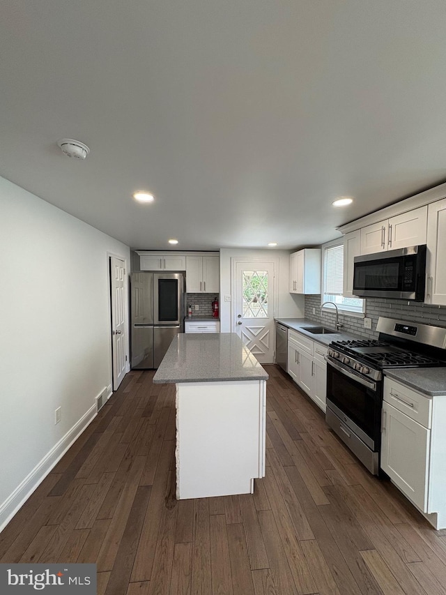 7915 New Second St, Elkins Park, PA 19027 - kitchen with appliances with stainless steel finishes, a sink, decorative backsplash, white cabinetry, and dark wood finished floors