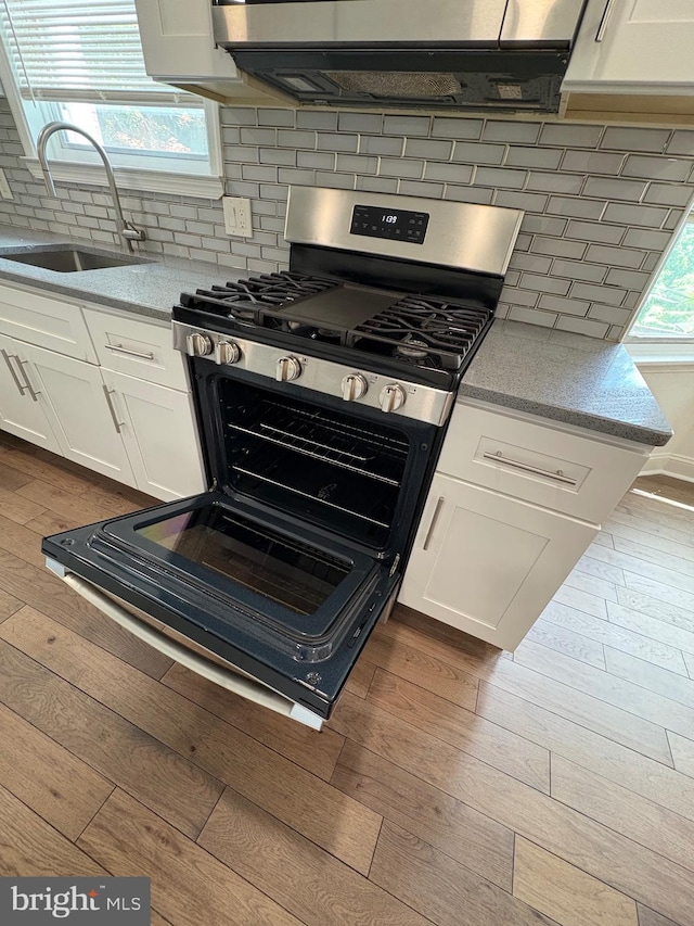 7915 New Second St, Elkins Park, PA 19027 - kitchen with a sink, gas range, dark wood-style floors, tasteful backsplash, and white cabinets