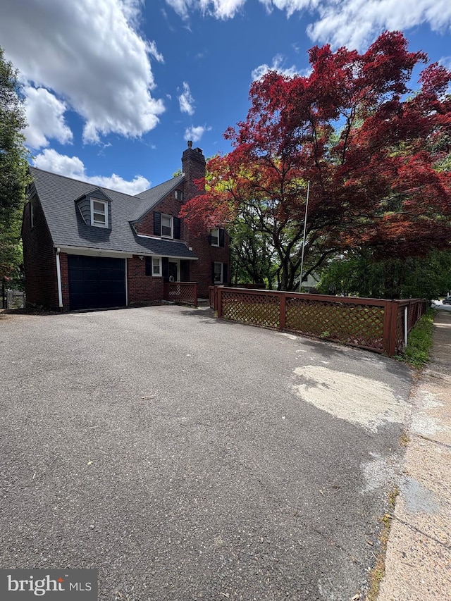 7915 New Second St, Elkins Park, PA 19027 - view of front of house with brick siding, a chimney, an attached garage, driveway, and roof with shingles