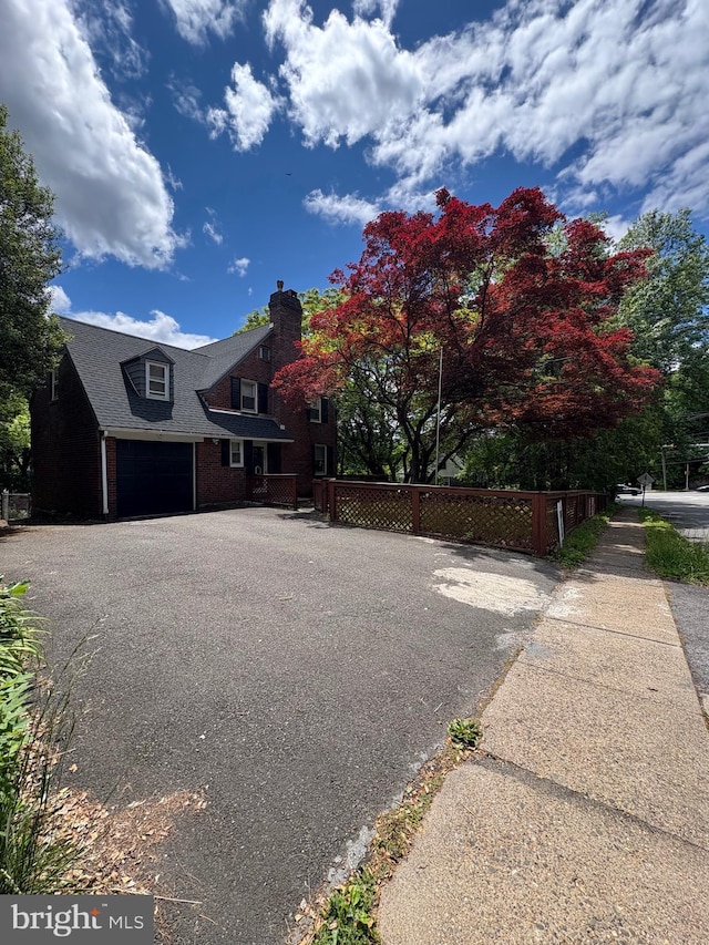 7915 New Second St, Elkins Park, PA 19027 - view of side of home with a chimney, asphalt driveway, an attached garage, and brick siding