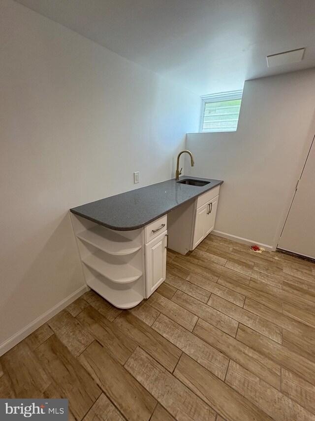 7915 New Second St, Elkins Park, PA 19027 - kitchen with open shelves, a sink, light wood-style flooring, white cabinets, and baseboards