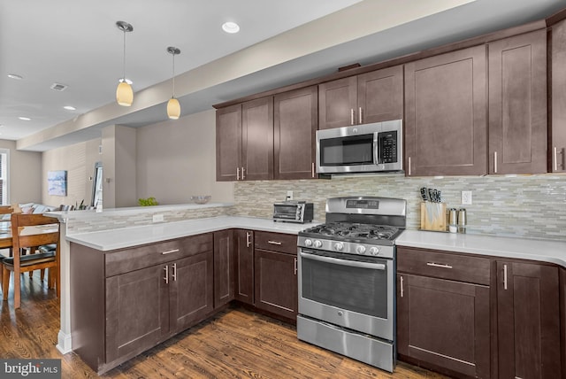 kitchen with dark brown cabinetry, a peninsula, appliances with stainless steel finishes, and light countertops
