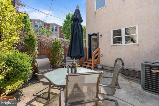 view of patio featuring central AC, outdoor dining space, fence, and entry steps