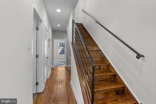 staircase featuring recessed lighting, wood finished floors, and baseboards
