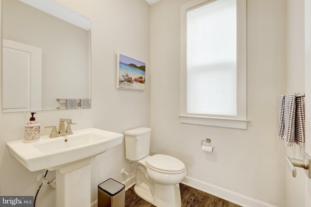 half bathroom with wood finished floors, toilet, and baseboards