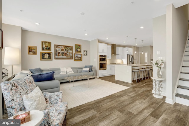 living area with stairs, wood finished floors, and recessed lighting