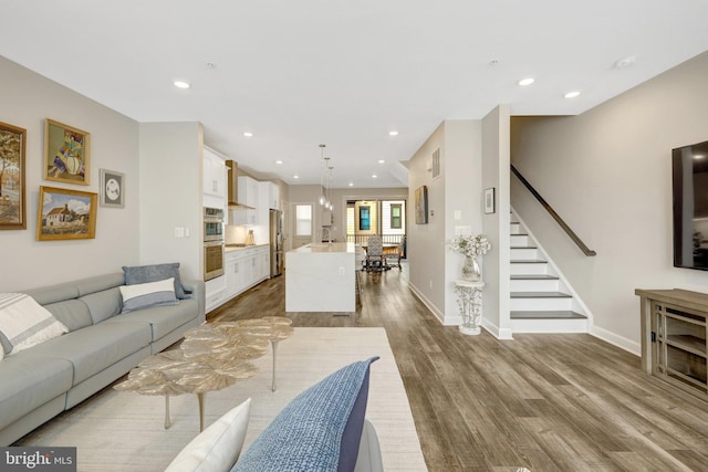 living room with wood finished floors, stairs, baseboards, and recessed lighting
