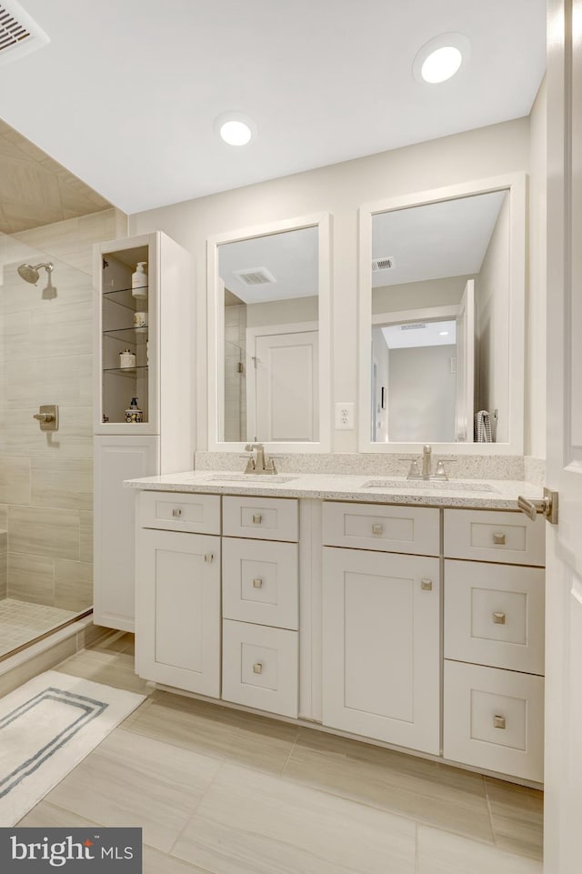 full bath with a tile shower, double vanity, and tile patterned floors
