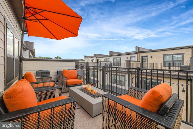 view of patio with central AC, an outdoor living space with a fire pit, and a balcony