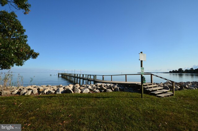 view of dock featuring a water view and a yard