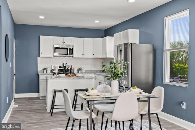 kitchen featuring appliances with stainless steel finishes, white cabinetry, light wood-type flooring, and baseboards