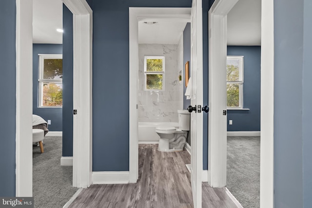 full bathroom with wood finished floors, toilet, and baseboards