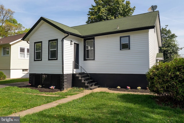 rear view of house featuring entry steps and a lawn