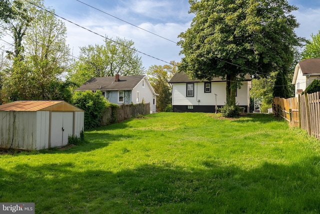 view of yard with fence, a storage unit, and an outbuilding
