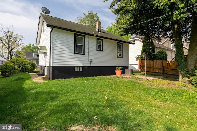 rear view of house with fence, a chimney, and a yard