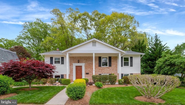 split foyer home with brick siding and a front lawn