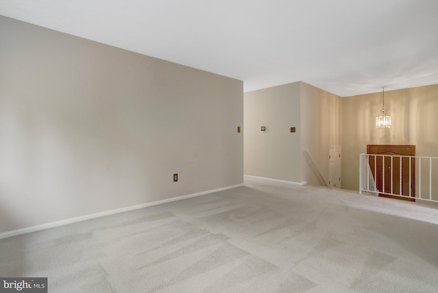 empty room with baseboards, light carpet, and a notable chandelier