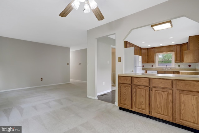 kitchen featuring freestanding refrigerator, a ceiling fan, light colored carpet, light countertops, and a sink